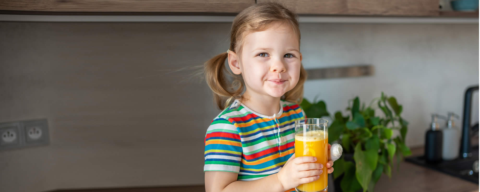 Little girl enjoying orange juice thickened with Slõ Syrup. Dysphagia drinks thickeners.