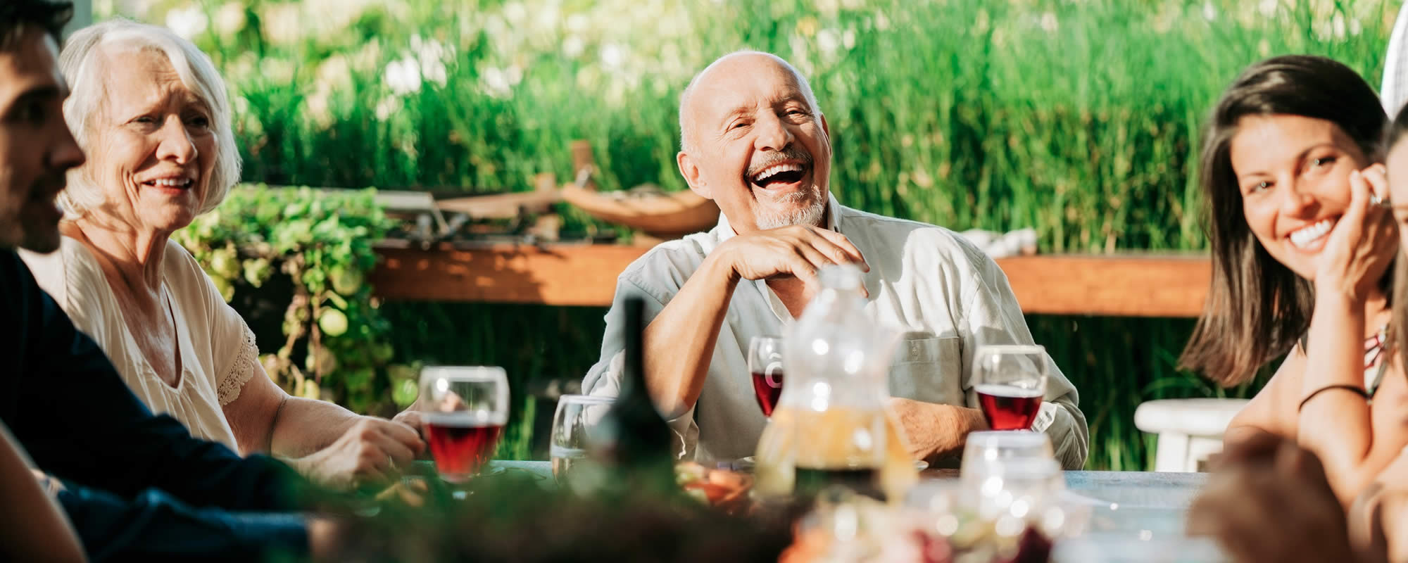 A man enjoying a glass of wine with friends which has been made dysphagia friendly with liquid drinks thickener Slõ Syrup. Dysphagia drinks thickeners.